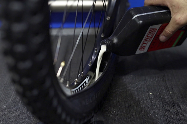 pouring tubeless sealant into a tyre