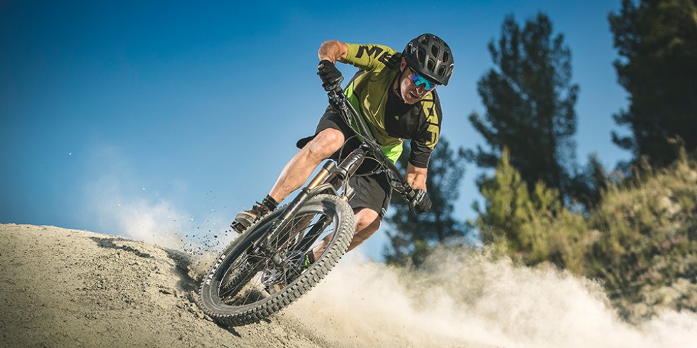 A mountain biker riding a Merida full-suspension bike, wearing Merida cycle clothing