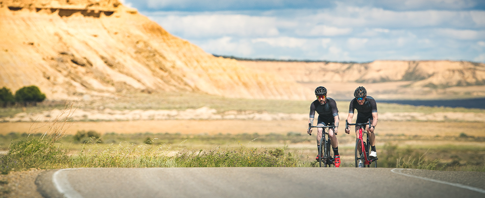 Two cyclists riding along a rural road on Merida Reacto road bikes