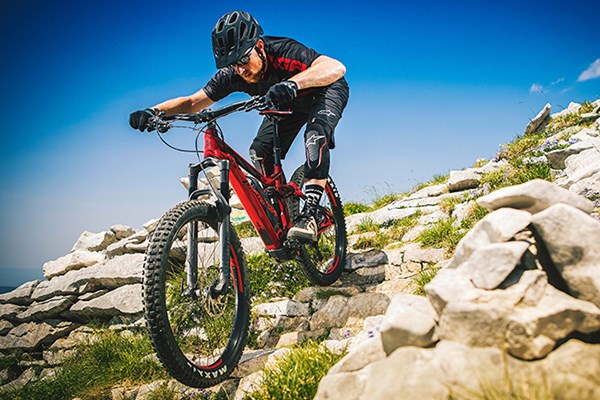 Mountain biker descending down a rocky trail on a full-suspension MTB