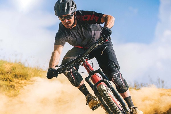 Mountain biker riding through a corner on dry, loose trail