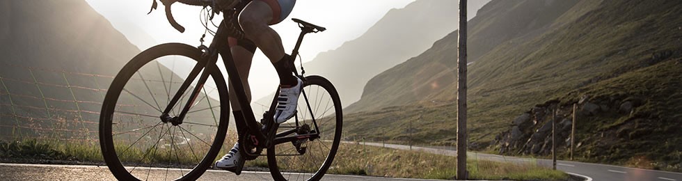 Road cyclist climbing mountain silhouette