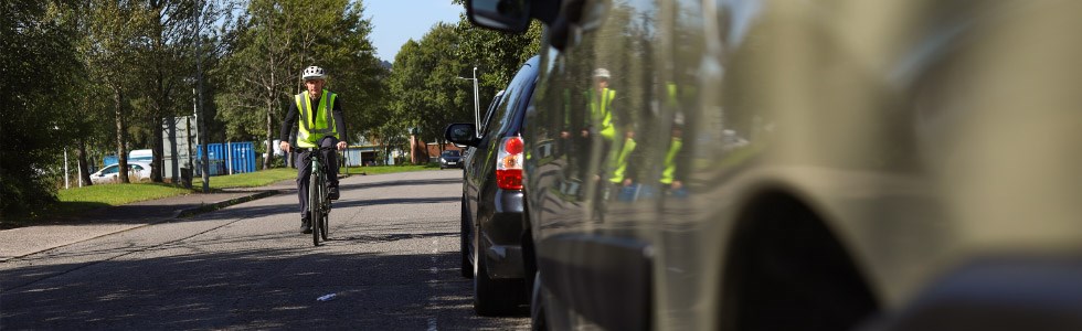 cyclist passing a parked car on the road