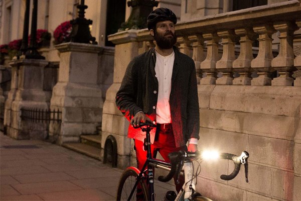 Cyclist standing by bike with lights on