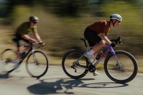 two road cyclists escending around a corner on a summer day