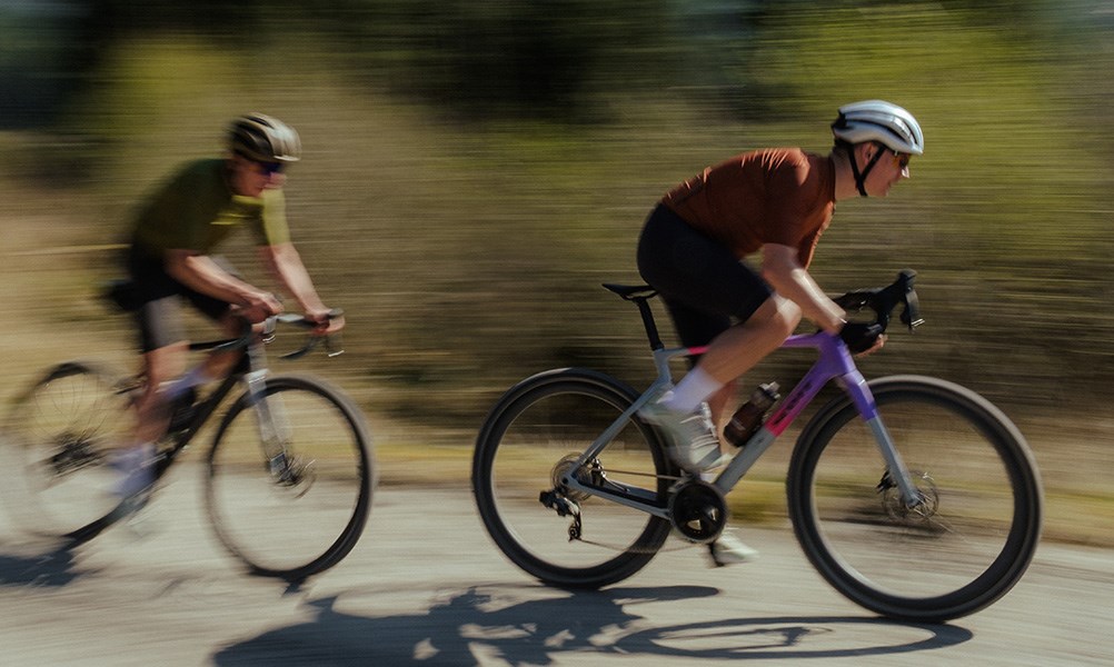 two gravel riders raiding fast on a warm day in Wales - pan shot