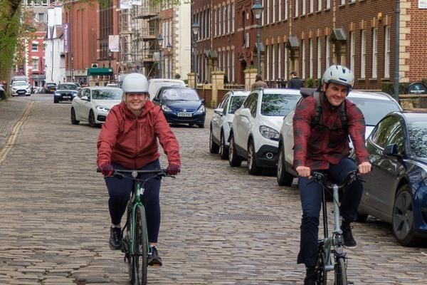 Two cyclists riding along a cobbled street in Bristol UK