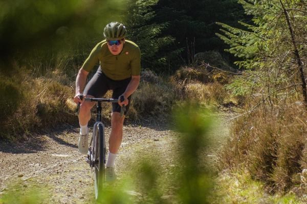 Gravel cyclist climbing on up a grave track on a summer day