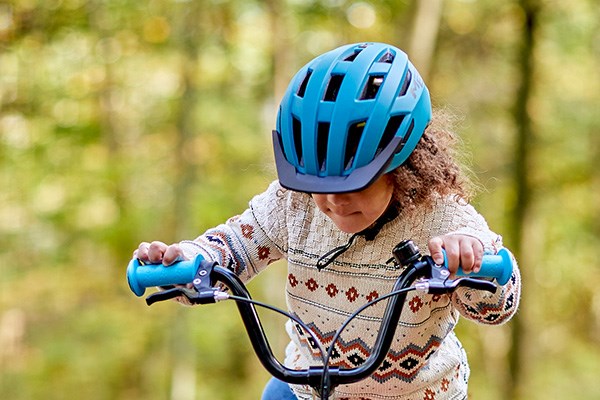 Child gettign on a bike wearing a bike helmet