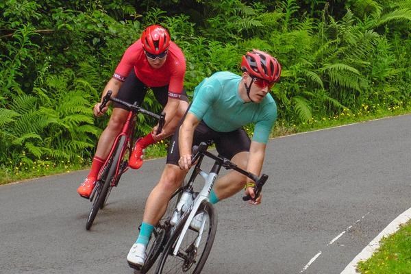 two road cyclists escending around a corner on a summer day