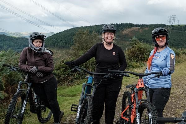 three female mountain bike riders relaxing at the trail head