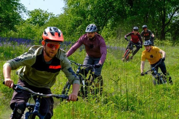 5 mtb riders riding down a trail together