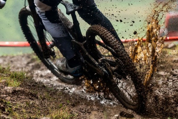 MTB DH racer splashing through puddle