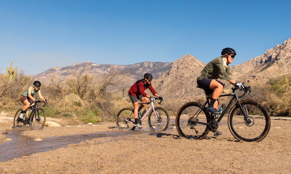 Three gravel cyclists riding through a river