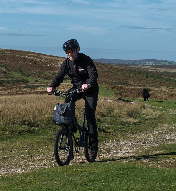 Riding the Brompton Electric G line up an off-road climb on a sunny winter day