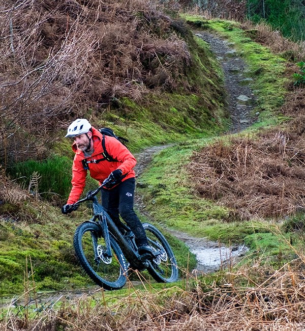 Mountain biker riding Cube Stereo Hybrid 160 HPC SLX e-bike on twisty trail