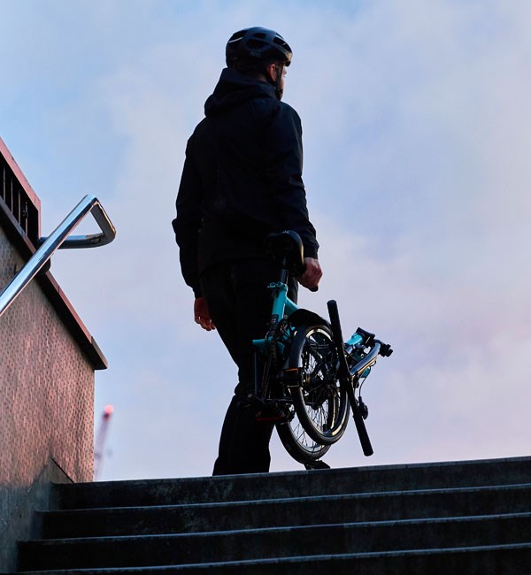 A folded Superlight Brompton, easily being carried up a flight of stairs