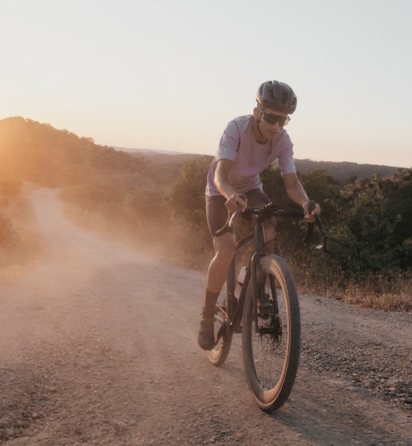 Gravel rider on dry grave track at sunrise