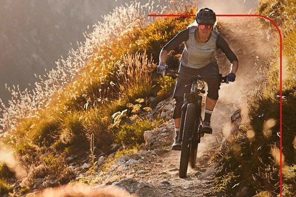 Female cyclist on an electric mountain bike descending a sunny hillside