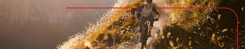 Female cyclist on an electric mountain bike descending a sunny hillside