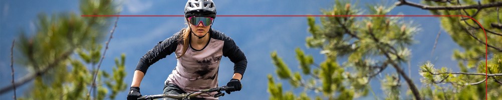 A mountain biker riding a Merida electric hardtail mountain bike through an overgrown trail