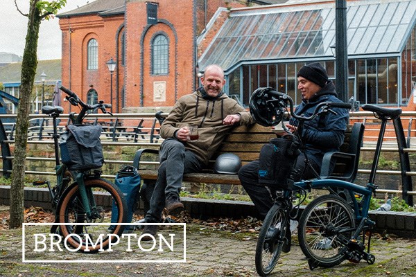 Two cyclists with Brompton folding bikes sitting with a coffee