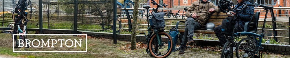 Two cyclists with Brompton folding bikes sitting with a coffee