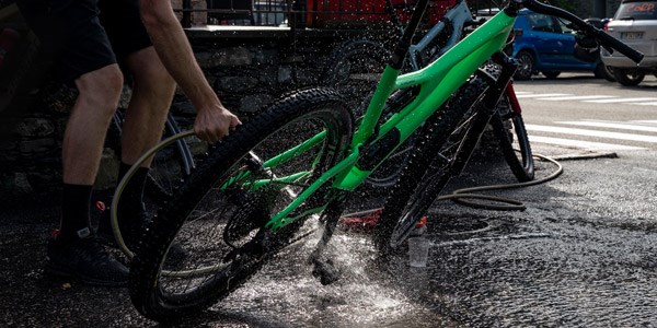 A mountain biker cleaning their wheels &amp; tyres