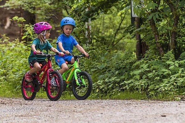 Two kids ride on a gravel trail